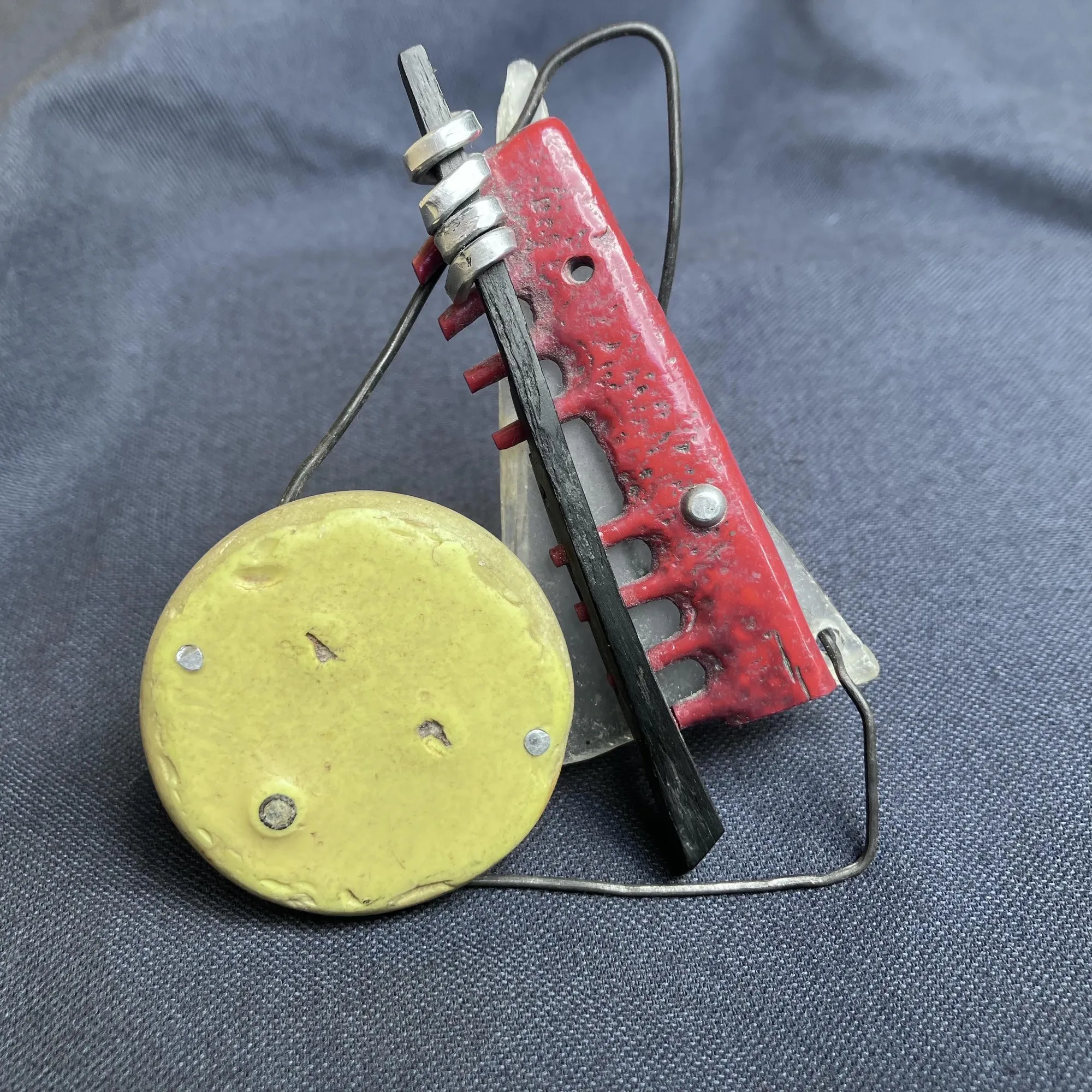 Detail of red and yellow found-object pieces mounted on denim